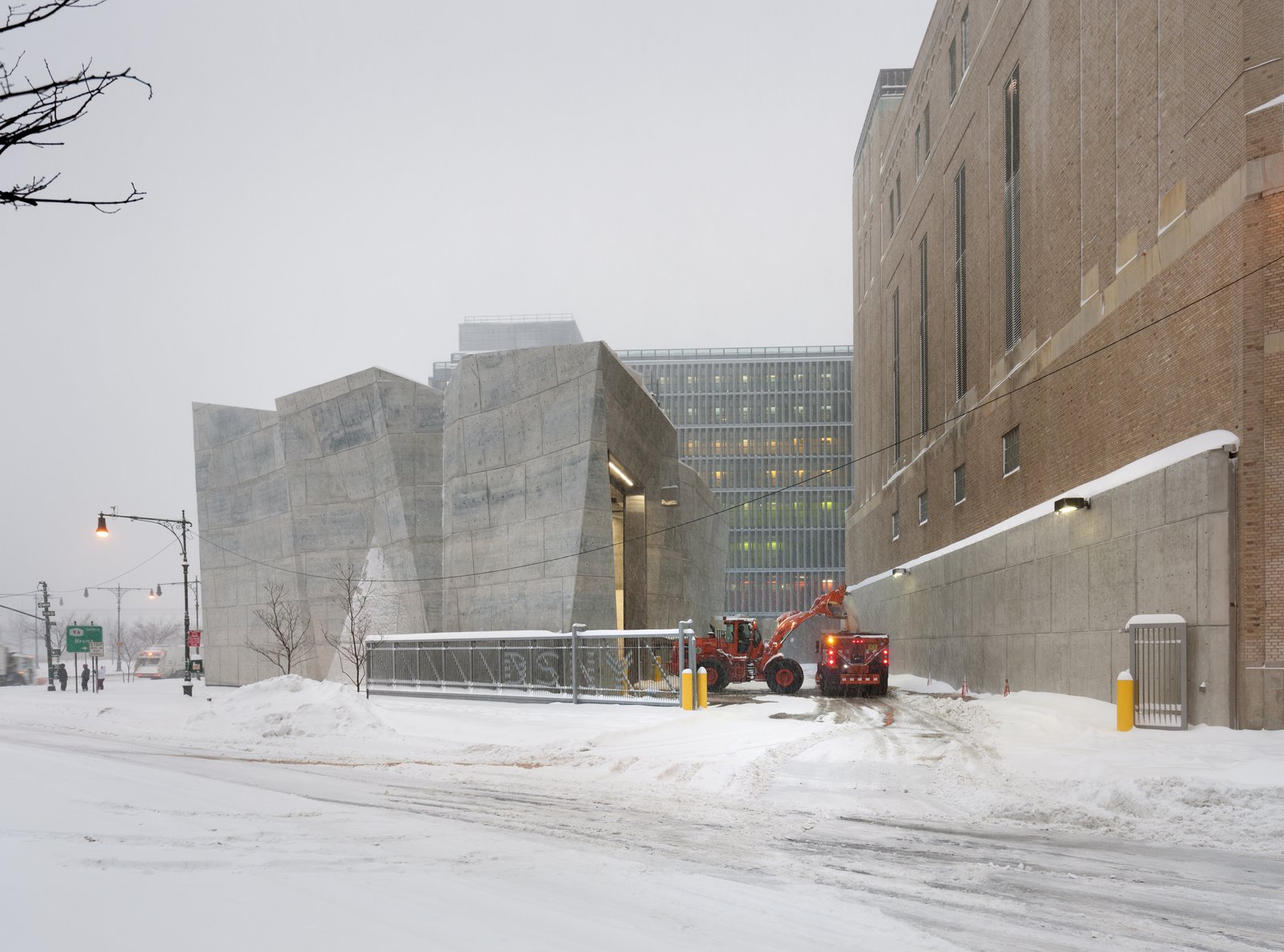 A view of the Salt Shed on a snowy day with two maintenance vehicles using the structure.