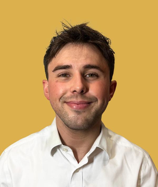 Headshot of Jack Ramsdale in a white shirt against a yellow background.