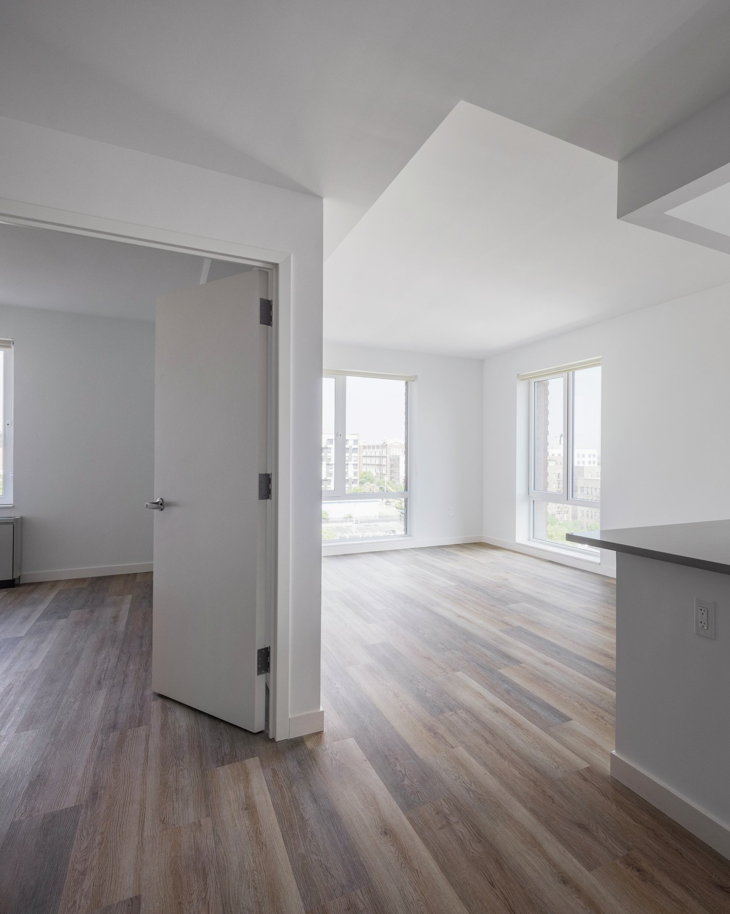 Bright apartment interior with large windows, wood floors, and a modern kitchen.