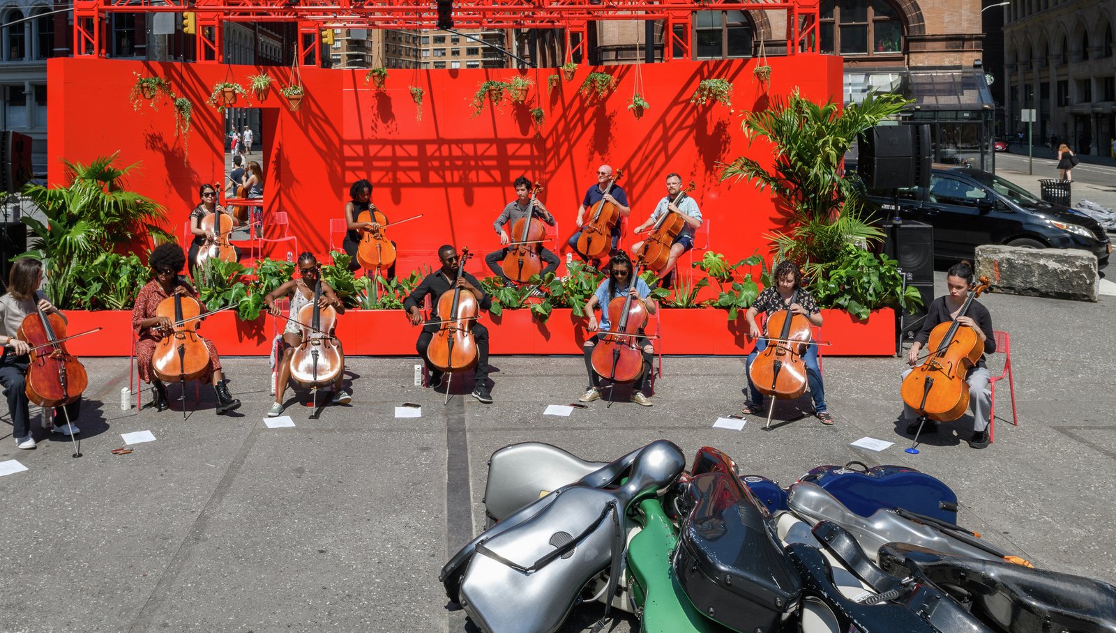 A group of cellists perform a concert on a red stage in Astor Place.