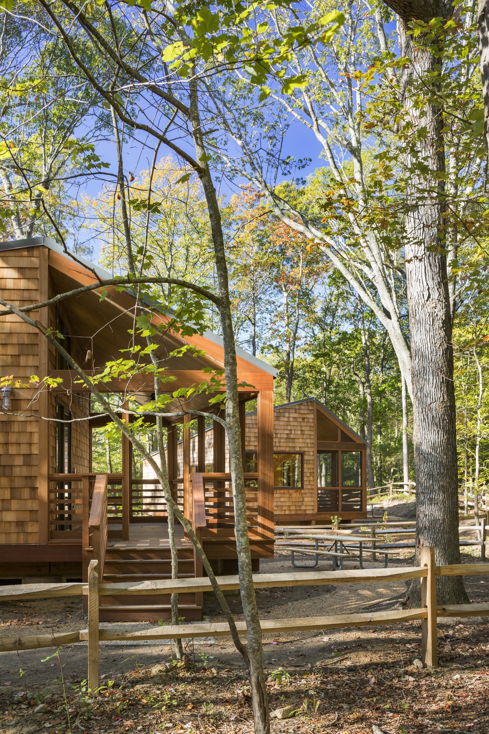 Wooden cabins with screened porches surrounded by trees and fencing.