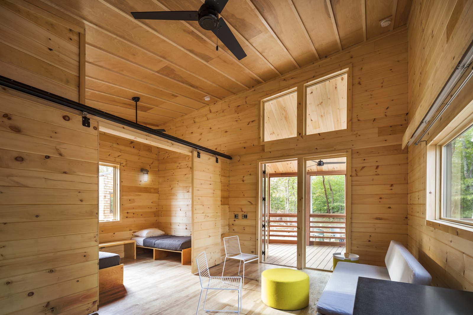 Bright cabin interior with natural wood walls, sliding doors, and outdoor views.