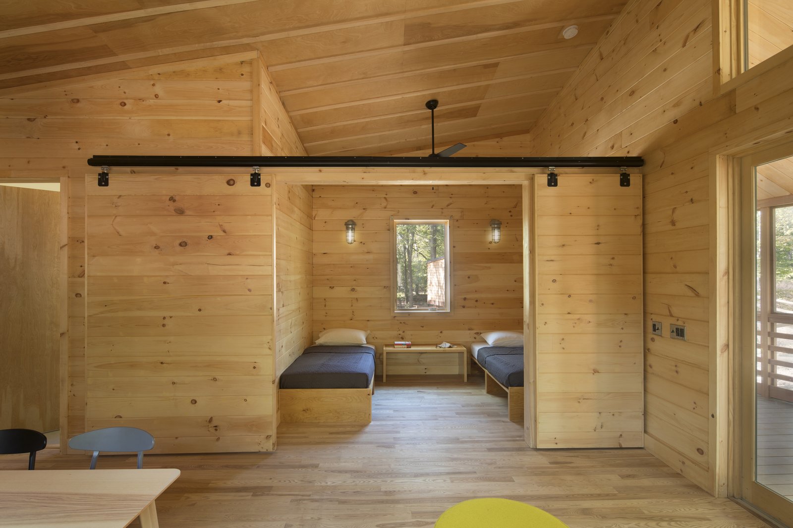 Cabin interior with natural wood paneling and sliding barn door.