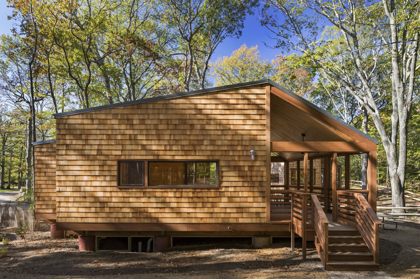 Wooden cabin with cedar shingles and an elevated screened porch.