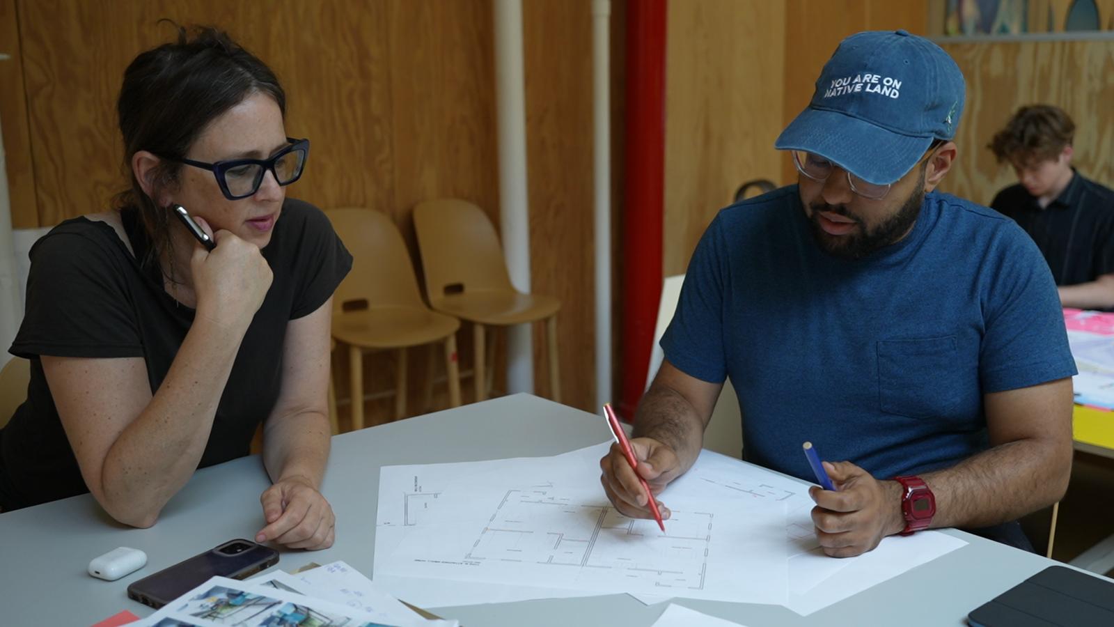 Two WXY employees use flexible work space to collaborate on architectural drawings.