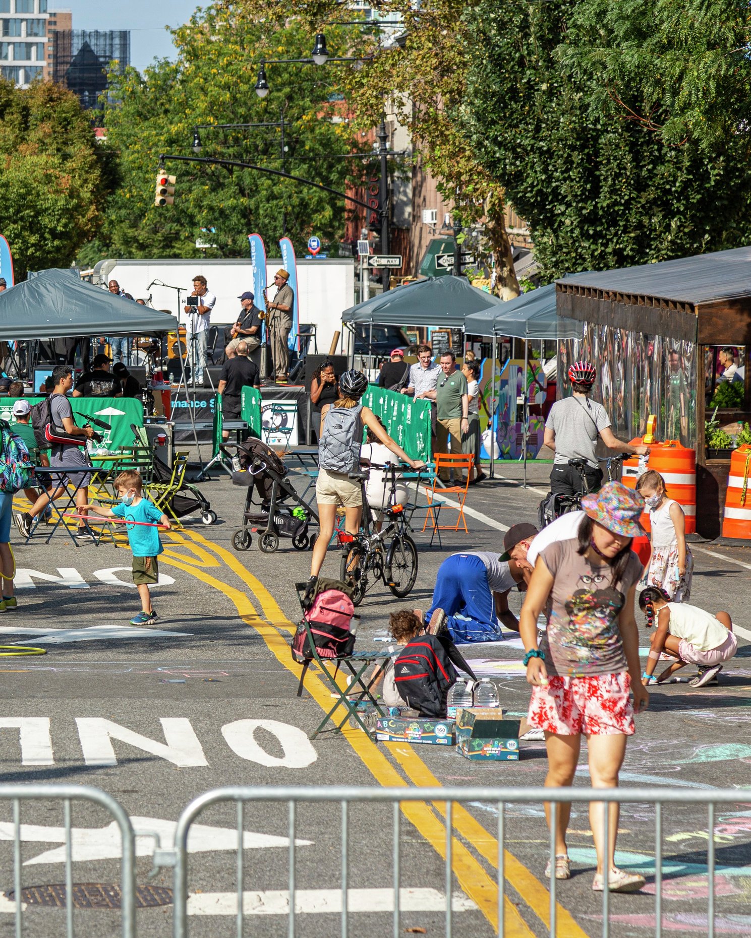 People enjoying an open streets event with activities, tables, and live performances.