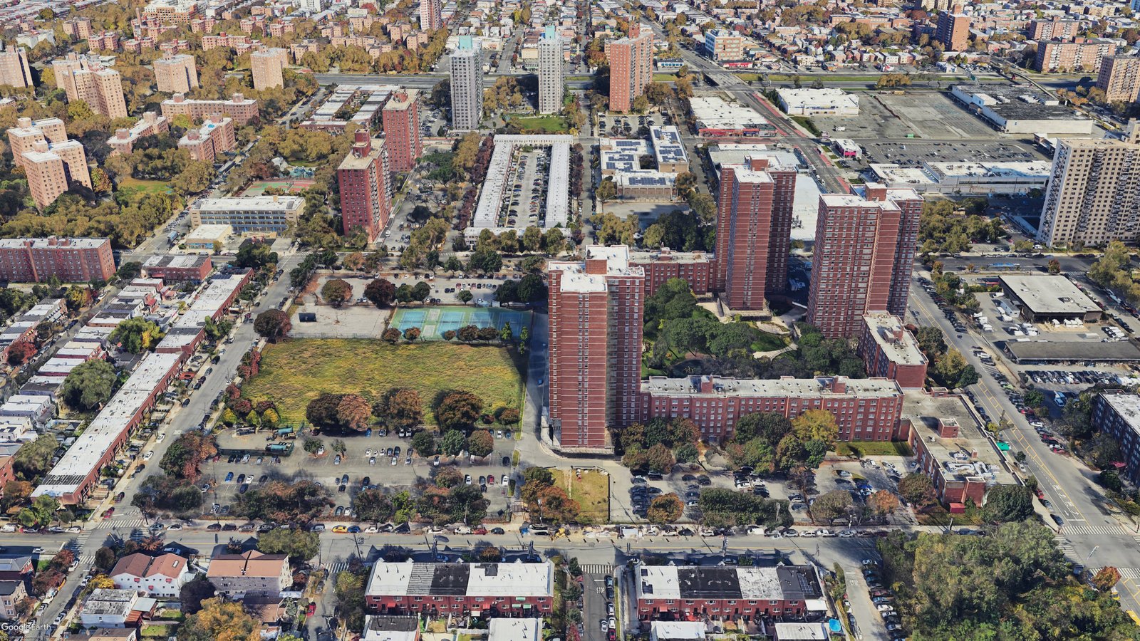 Aerial view of a residential area with high-rise towers, open green spaces, and surrounding streets.