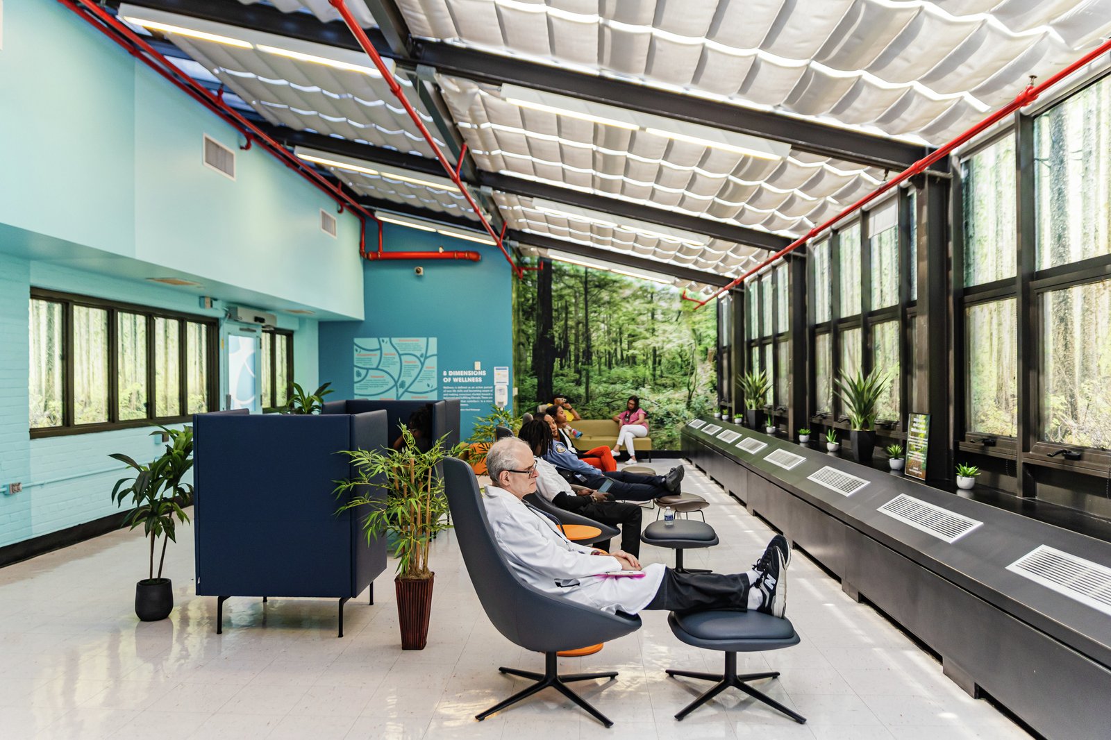 Healthcare workers unwind in a bright wellness space featuring natural light, forest murals, and comfortable seating.